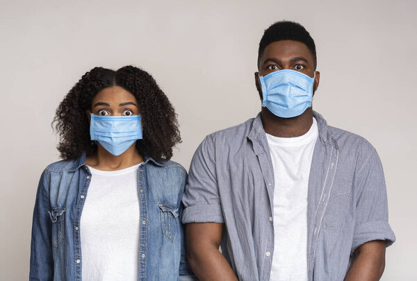 Danger Of Coronavirus. Scared black couple posing in protective medical masks