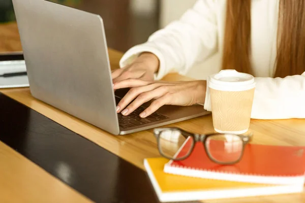 Jenta jobber. Briller, notisbøker og kaffe på bordet – stockfoto