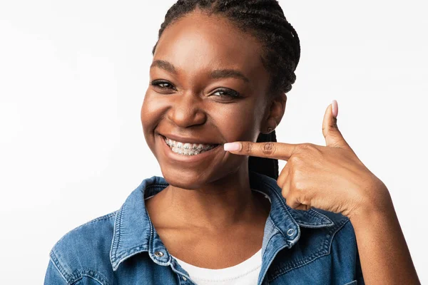 African Girl In Braces Pointing Finger At Smile, White Background — Stockfoto