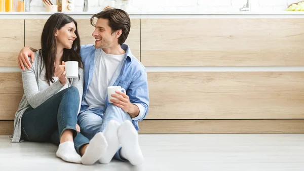 Young couple enjoying coffee, sitting on floor at kitchen — Φωτογραφία Αρχείου