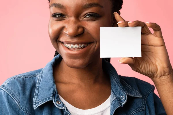 African Girl In Braces Showing Orthodontists Visiting Card, Pink Background — стокове фото