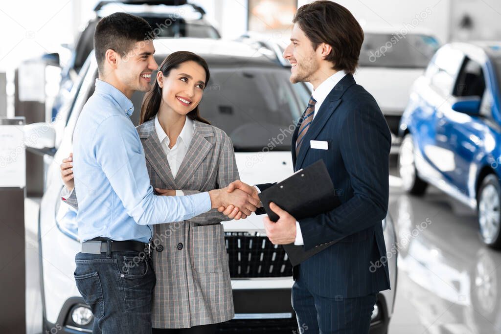 Car Dealer Shaking Hands With Buyers After Successful Deal