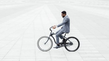 Handsome afro businessman riding his bike to work, isolated