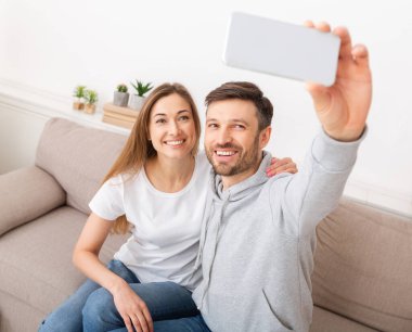 Happy young couple taking selfie of moving in new apartment