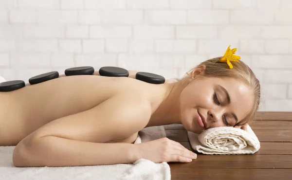 Girl with closed eyes on the table takes spa stone massage — Stock fotografie