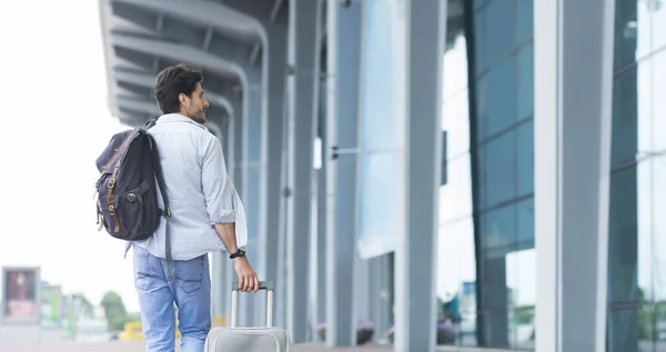Salidas Internacionales. Hombre viajero caminando con equipaje cerca del aeropuerto, terminal de facturación — Foto de Stock