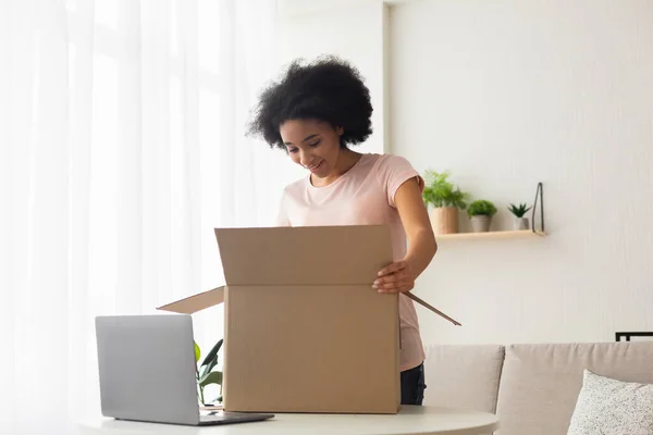 Surprised american young woman with laptop opens box — Stockfoto