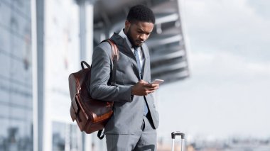 Businessman Using Smartphone Reading Message About Trip Cancellation At Airport