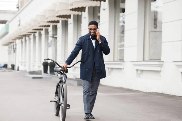 Hombre de negocios guapo hablando por teléfono sosteniendo su bicicleta — Foto de Stock