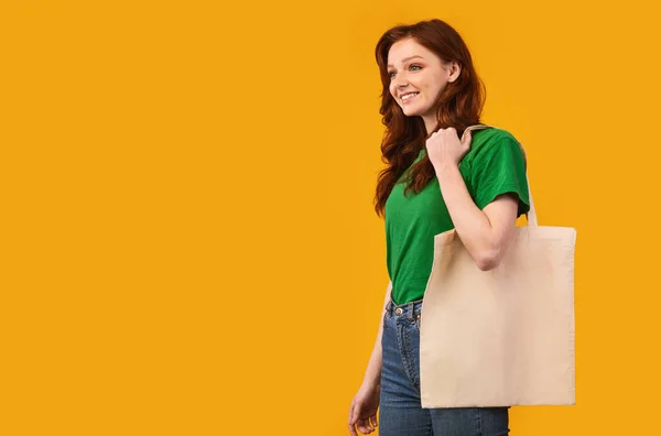 Cheerful Minimalist Girl Carrying Eco Tote Bag, Yellow Background — Stockfoto