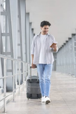 Happy Man Holding Passport And Tickets, Walking With Suitcase In Airport