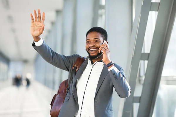 Feliz hombre de negocios saludando la mano hablando en el teléfono celular caminando en el aeropuerto — Foto de Stock
