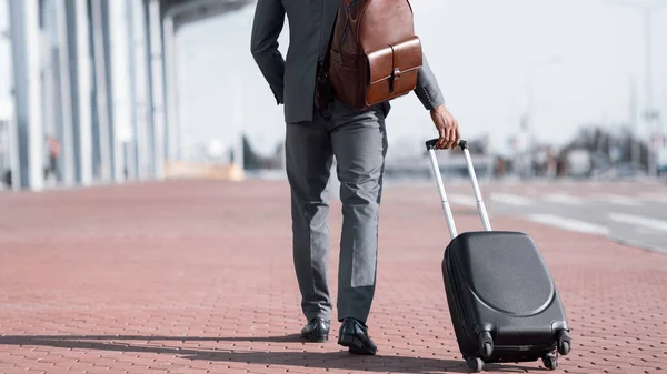 Uomo d'affari con valigia che cammina di nuovo alla macchina fotografica vicino all'aeroporto, ritagliato — Foto Stock
