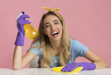 Housewife holds spray in hand and wipes rag of table