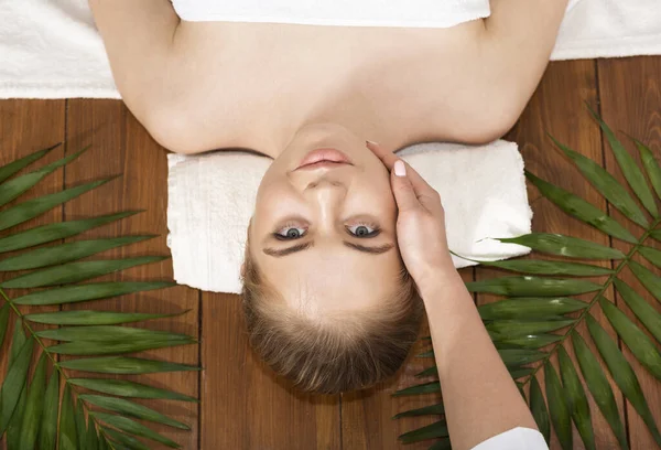 Smiling woman on massage table with palm leaves — Stock fotografie