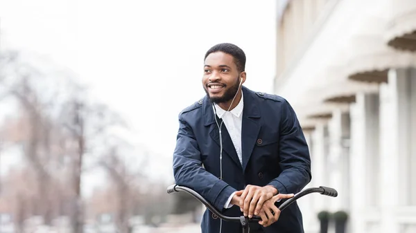 Black man in earphones riding bicycle and listening to radio — Stok fotoğraf