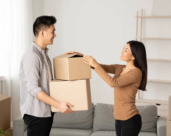 Happy asian family packing cardboard boxes in new flat — ストック写真