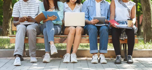 Group of students sitting on bench outdoors preparing for classes together — Stockfoto