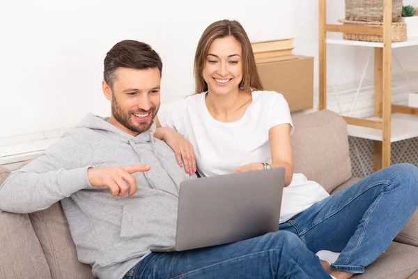 Прекрасные муж и жена сидят в новой квартире с ноутбуком — стоковое фото