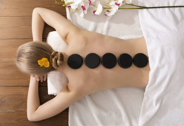 Conceito de massagem de pedra Spa. Menina na mesa de massagem — Fotografia de Stock