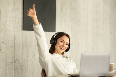 Kulaklıklı serbest bir kadın baş parmağını gösteriyor.