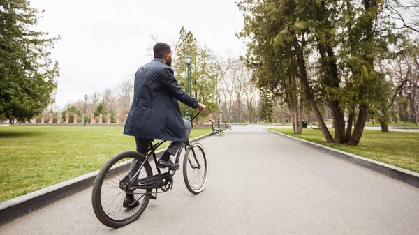 Bonito empresário afro andando de bicicleta no parque — Fotografia de Stock