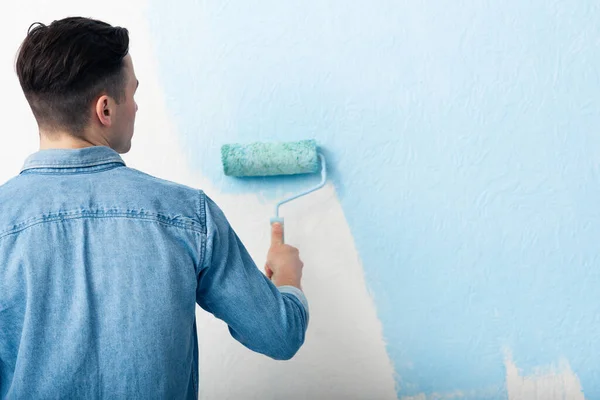 Hombre pintando pared interior con rodillo de pintura — Foto de Stock