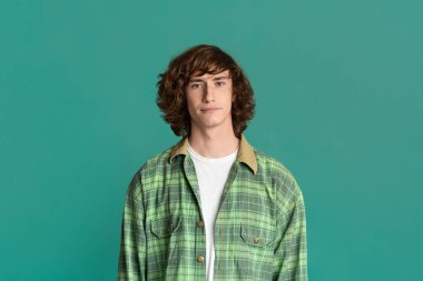 Renkli arka planda günlük kıyafetler giyen ciddi bir genç.