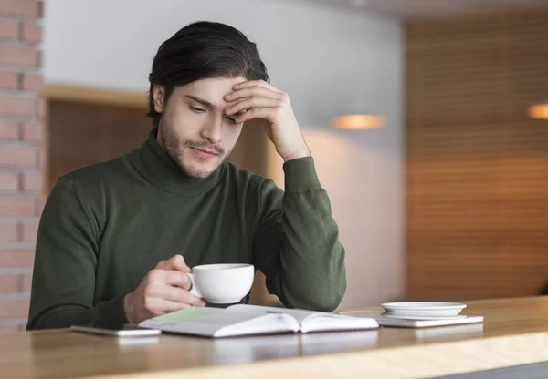 Sconvolto giovane seduto al caffè e bere caffè da solo — Foto Stock