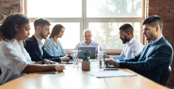 Kollegen, die während einer Besprechung am Schreibtisch im Büro sitzen — Stockfoto