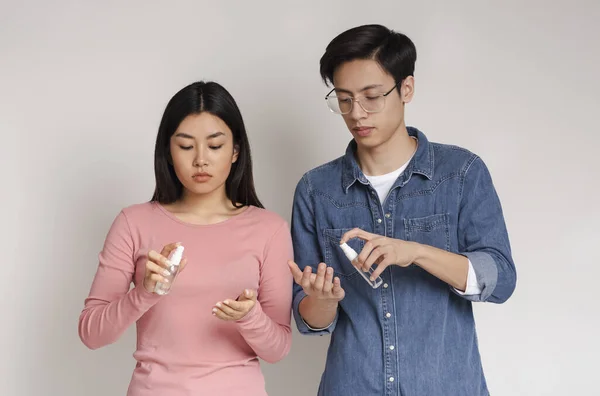 Précautions contre le coronavirus. Jeune couple chinois appliquant un spray antiseptique sur les mains — Photo