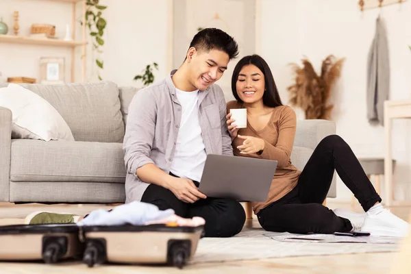 Casal alegre usando laptop planejamento viagem sentado no chão interior — Fotografia de Stock