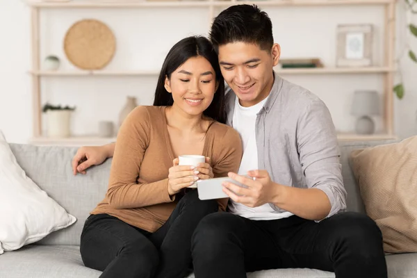 Casal coreano descansando em casa, usando telefone — Fotografia de Stock