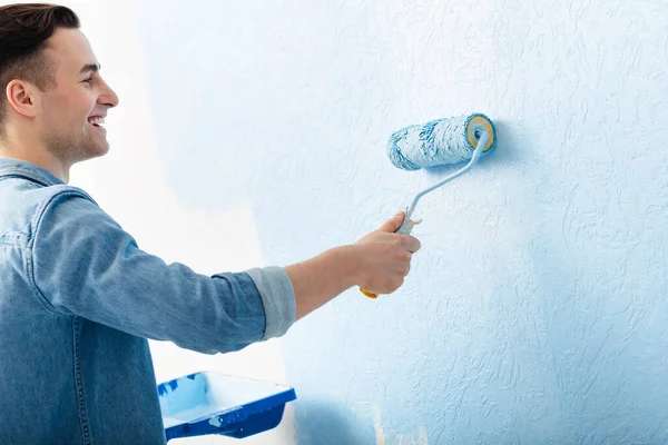 Männchen bemalt Wand mit Walze in blauer Farbe — Stockfoto