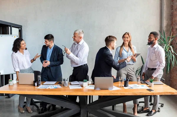 Різноманітні колеги обговорюють бізнес проект стоячи в сучасному офісі — стокове фото
