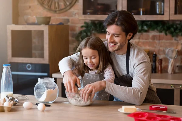 Батько і дочка роблять випічку на кухні разом, замішуючи тісто — стокове фото