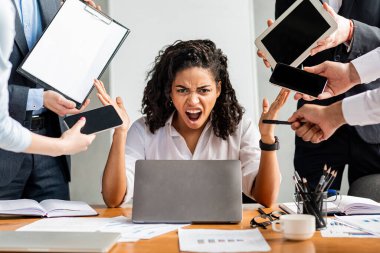 Öfkeli iş kadını laptopta oturmuş öfkeyle bağırıyor.