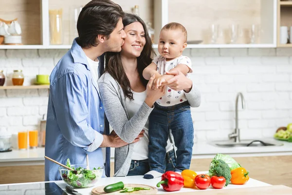 Junge Eltern umarmen ihren kleinen Sohn in der Küche — Stockfoto