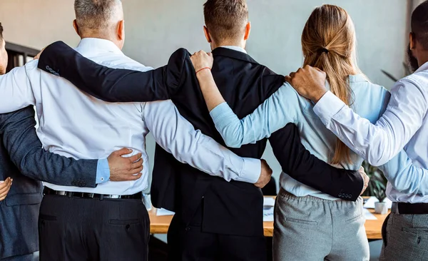 Coworkers Standing Back To Camera Embracing During Meeting In Office — Stock Photo, Image