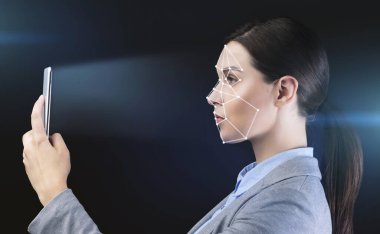 Biyometrik doğrulama. Siyah arkaplanda yüz tanıma sistemi kullanan akıllı telefonlu bir iş kadını
