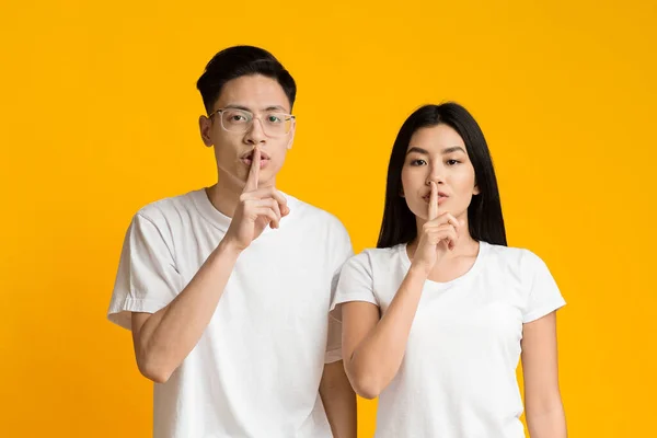 Sério asiático casal fazer silêncio sinal, manter os dedos indicador em lábios — Fotografia de Stock