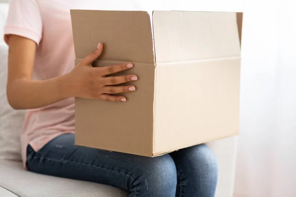 Afro-Amerikaans meisje met een kartonnen doos op haar knieën — Stockfoto