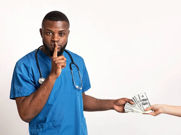 Terapeuta africano recebendo suborno e segurando o dedo nos lábios — Fotografia de Stock