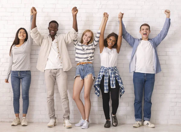 Vreugdevolle tieners heffen samengevoegd handen omhoog samen — Stockfoto