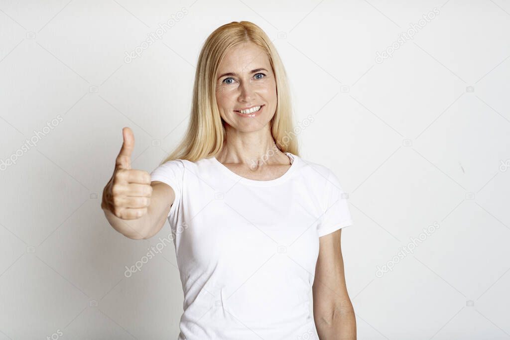 Portrait of mature smiling woman showing thumb up