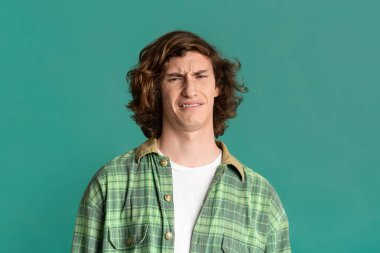 Turkuaz arka planda tiksindirici bir yüz ifadesi olan milenyum adamı.
