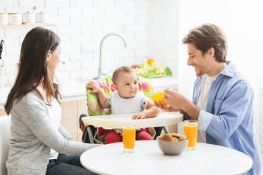 Genç ebeveynler oğlunu kahvaltıyla besliyor.