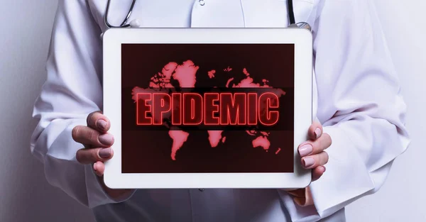 Medic holding tablet computer with world map and word EPIDEMIC on screen