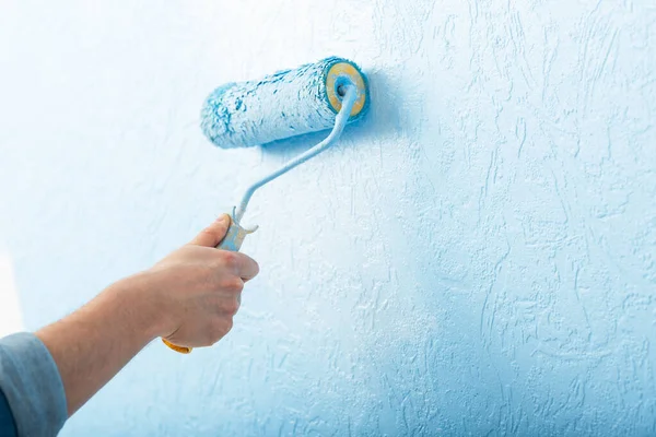 Mano masculina con rodillo colores textura pared en color azul — Foto de Stock