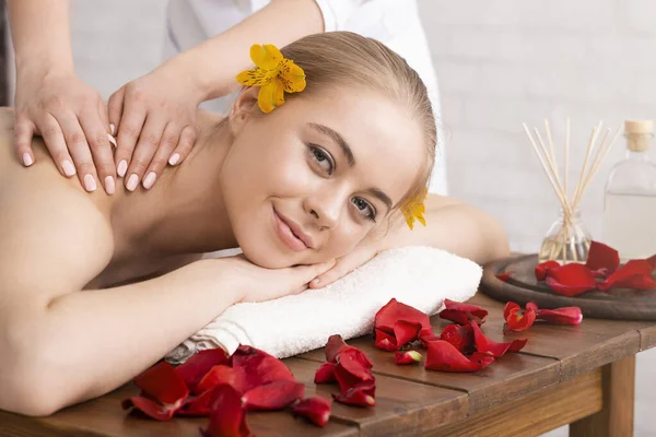 Lächeln Mädchen auf Tisch mit Blütenblättern hat Massage — Stockfoto